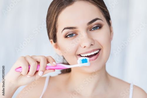 Beautiful smiling woman holding a toothbrush and toothpaste, fresh studio portrait