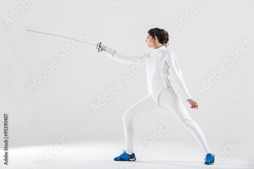 Portrait of woman wearing white fencing costume practicing with the sword