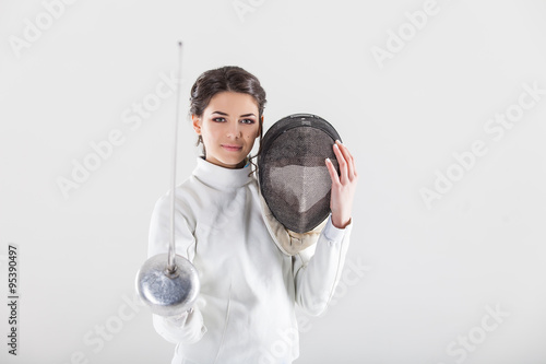 Slika na platnu Portrait of woman wearing white fencing costume practicing with the sword