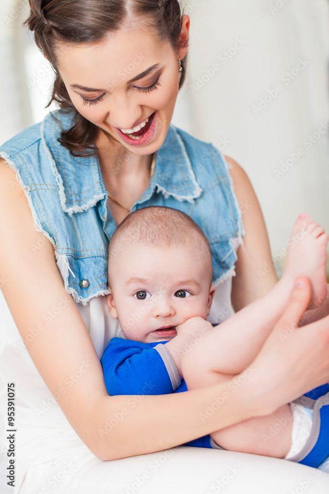 Happy family laughing faces, mother holding adorable child baby boy, smiling and hugging Happy family laughing faces, mother holding adorable child baby boy, smiling and hugging
