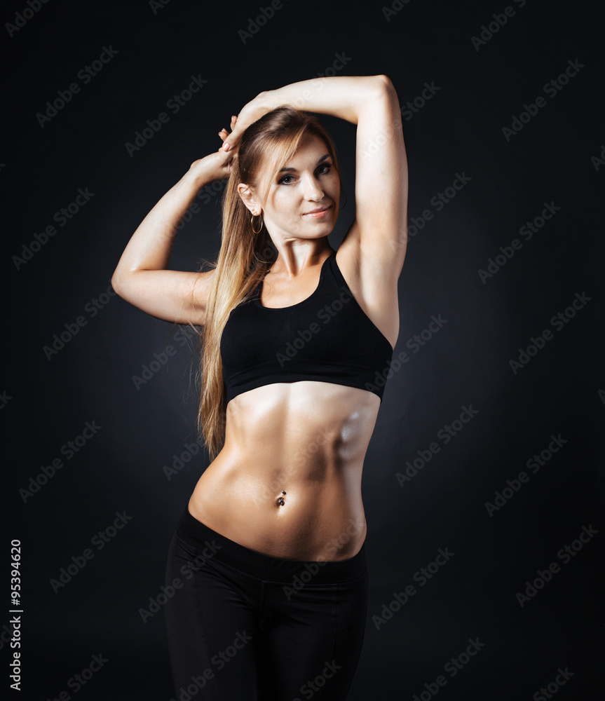 Fototapeta premium Muscular fitness woman with dumbbells on a dark background