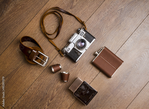 Vintage camera and leather belt on wooden floor