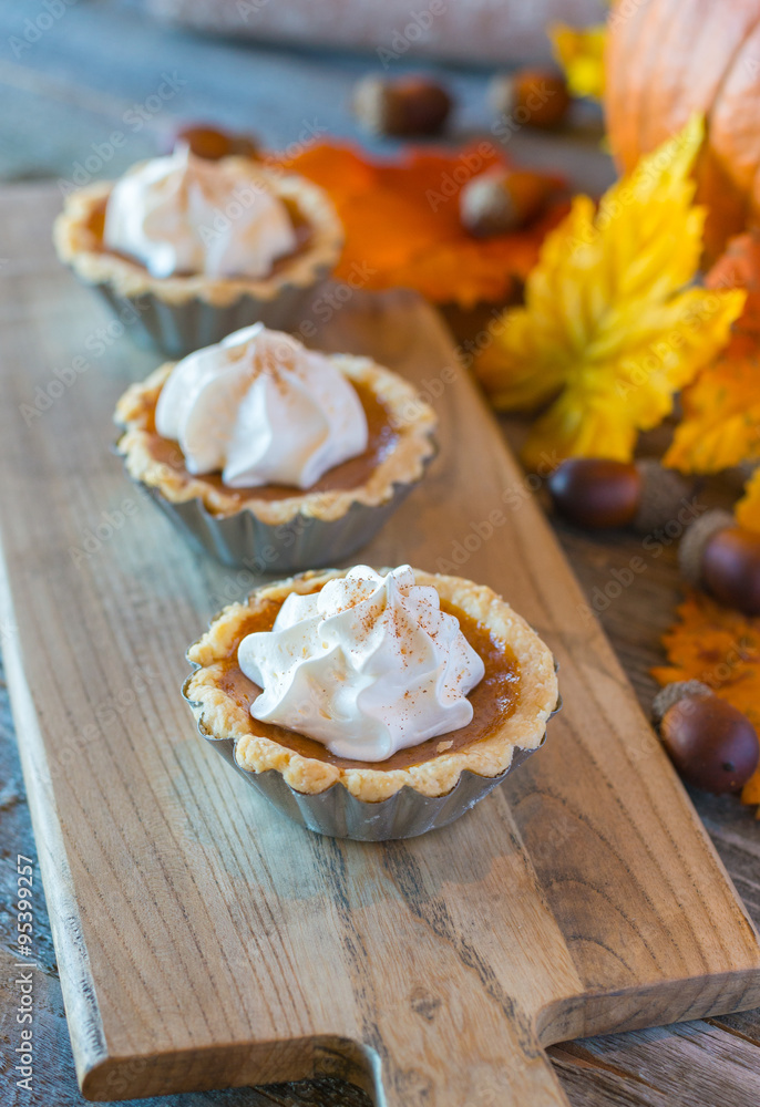 Miniature pumpkin pies displayed on a wood table Miniature pumpkin pies displayed on a wood table