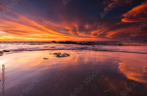 orange sunset with reflection on wet sand