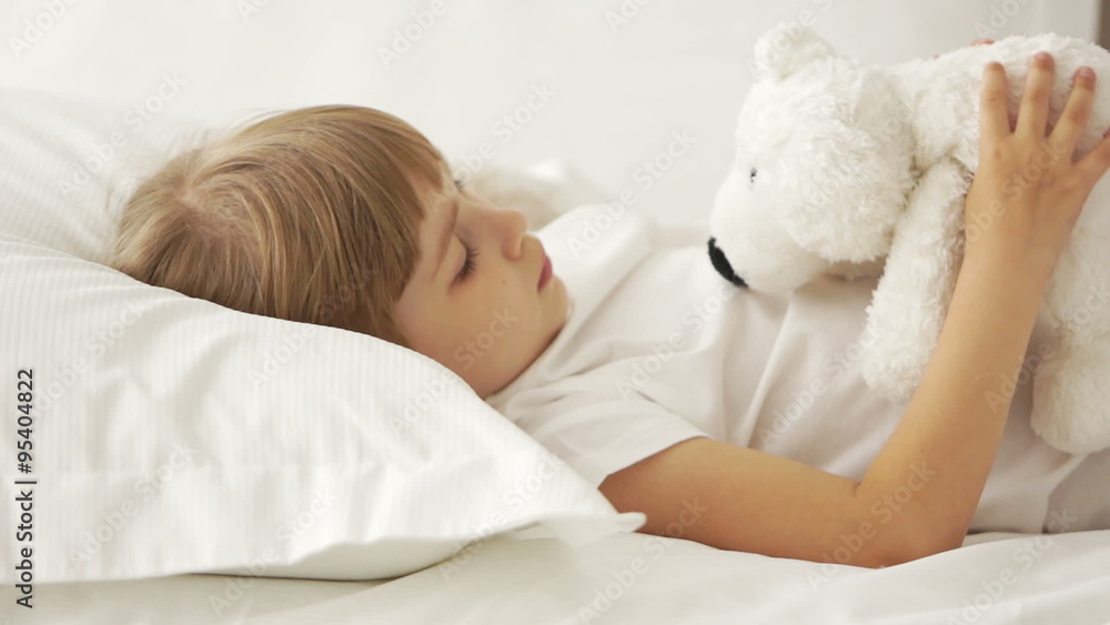 Little girl lying in bed and playing with teddy bear Little girl lying in bed and playing with teddy bear