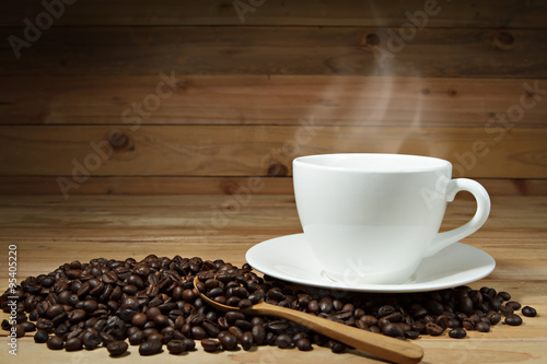 Coffee cup and coffee beans on wooden background.