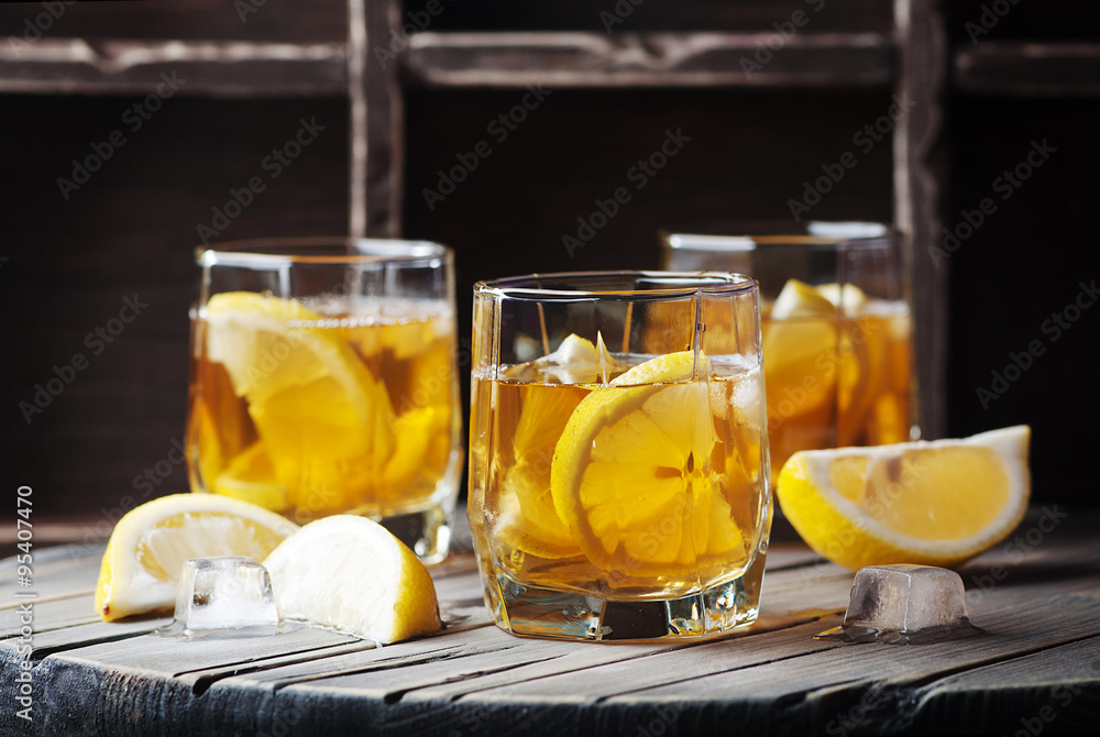 Cold whiskey with ice and lemon on the vintage table