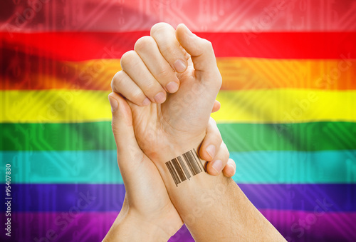 Barcode ID number on wrist and national flag on background - LGBT people photo