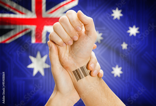 Barcode ID number on wrist and national flag on background - Australia