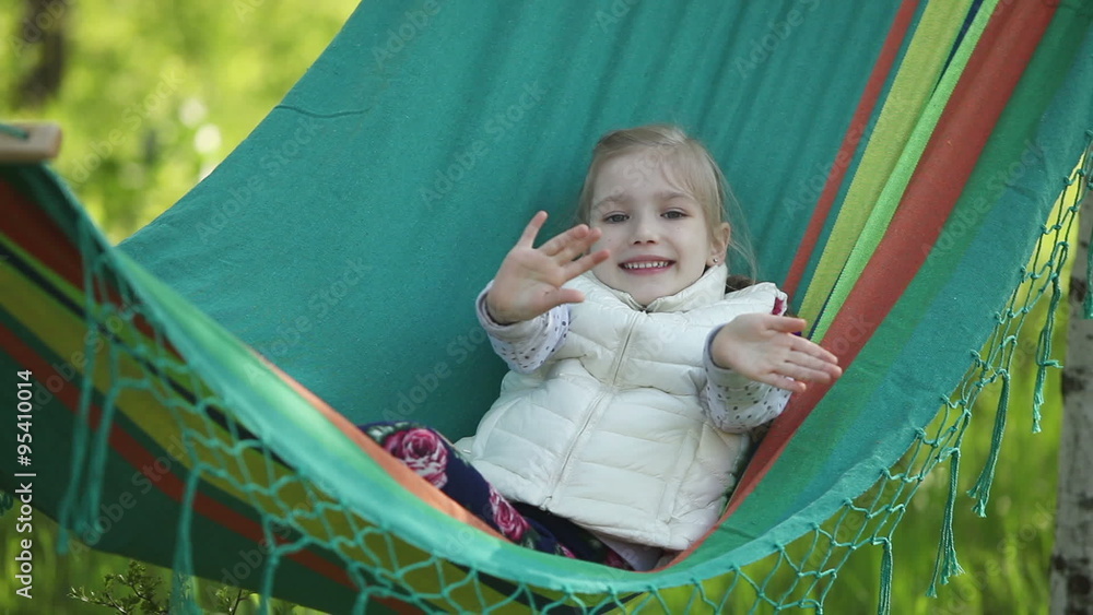 Smiling little girl in a hammock outdoor and looking to the camera Smiling little girl in a hammock outdoor and looking to the camera