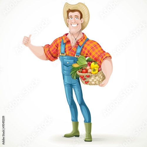 Cute young guy farmer with a big basket of vegetables showing th