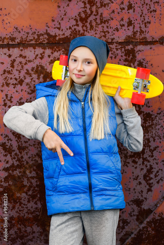 Smiling girl holding color plastic penny board or skateboards outdoor and showing Ok