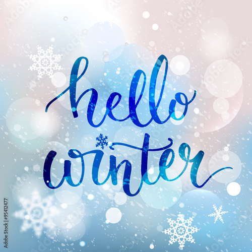 Hello winter text. Brush lettering at blue winter background with snowflakes and bokeh lights. Vector card design with custom calligraphy