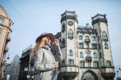 woman in gray coat and hat against the backdrop of a beautiful old building