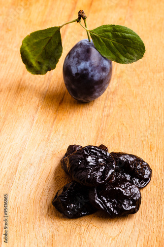 dried plums and fresh prune fruit on wooden table