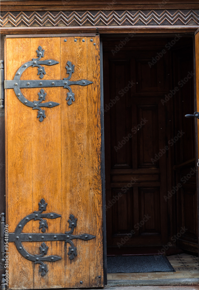 Ancient oak wood gate with decorative hinges forged in steel, half open Ancient oak wood gate with decorative hinges forged in steel, half open