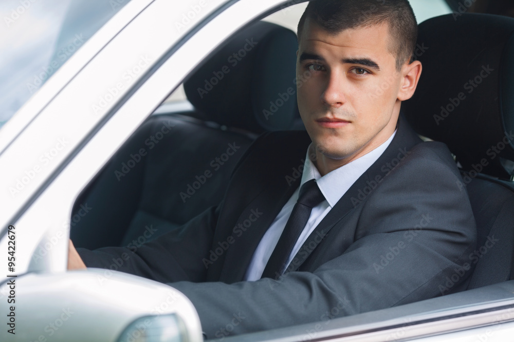 Portrait of a young businessman driving a car