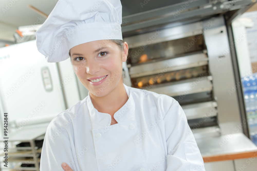 Female baker stood by bread oven