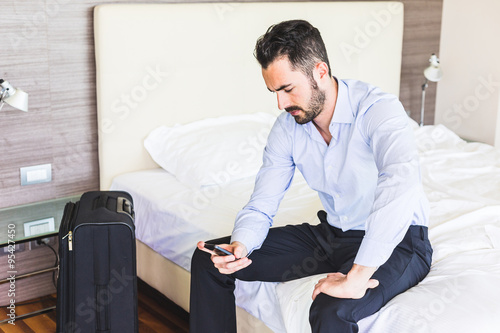 Businessman looking at smart phone in his hotel room