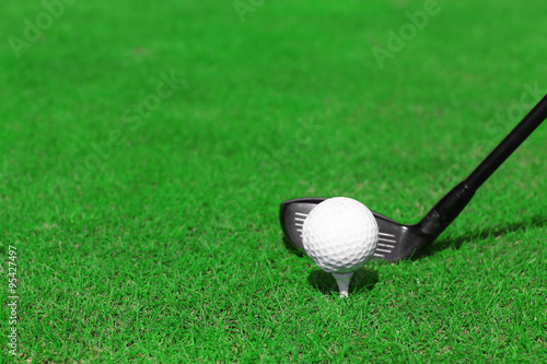 Golf club and ball on a green grass