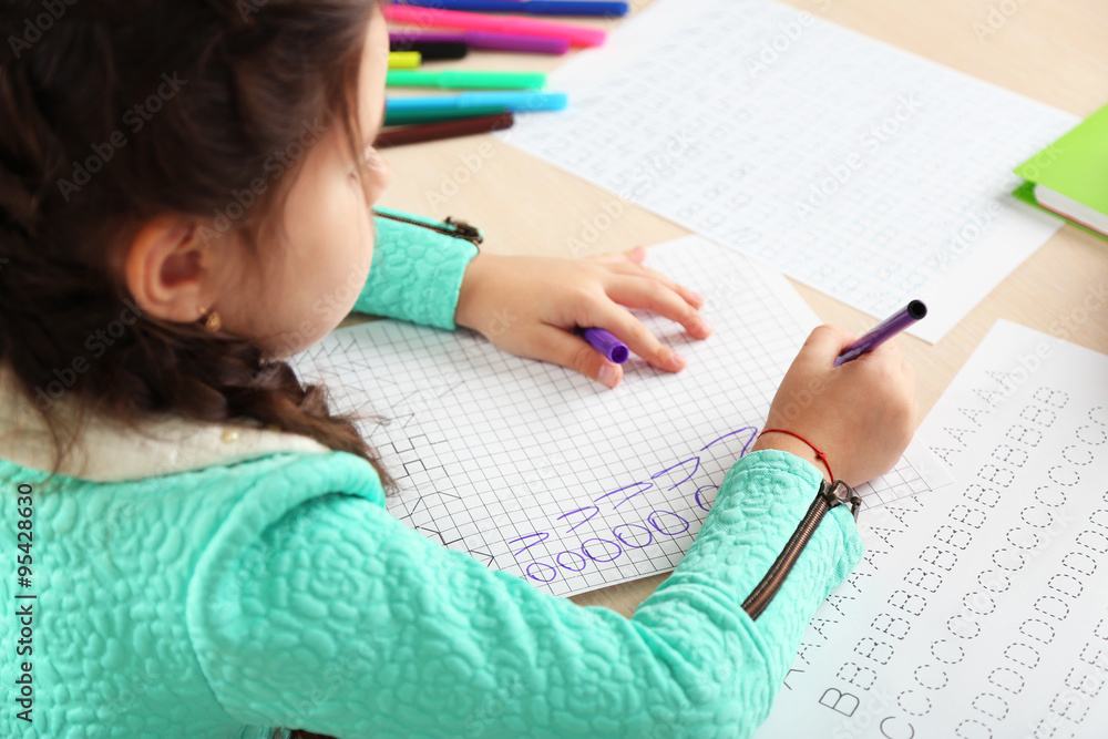 Cute little girl doing her homework, close-up Cute little girl doing her homework, close-up