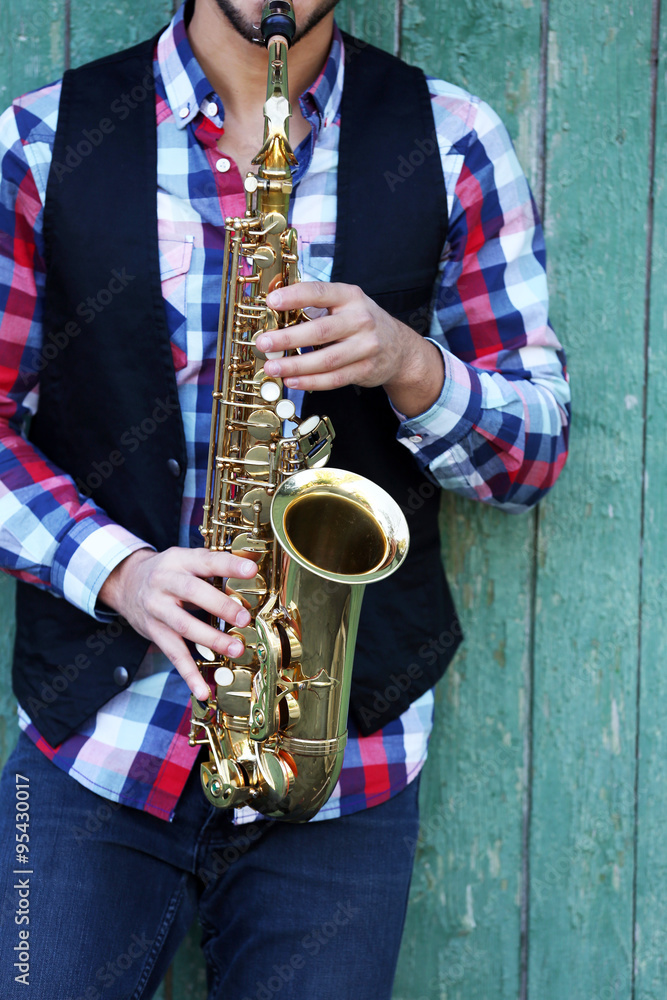 Obraz premium The musician plays saxophone on green wooden background, close up