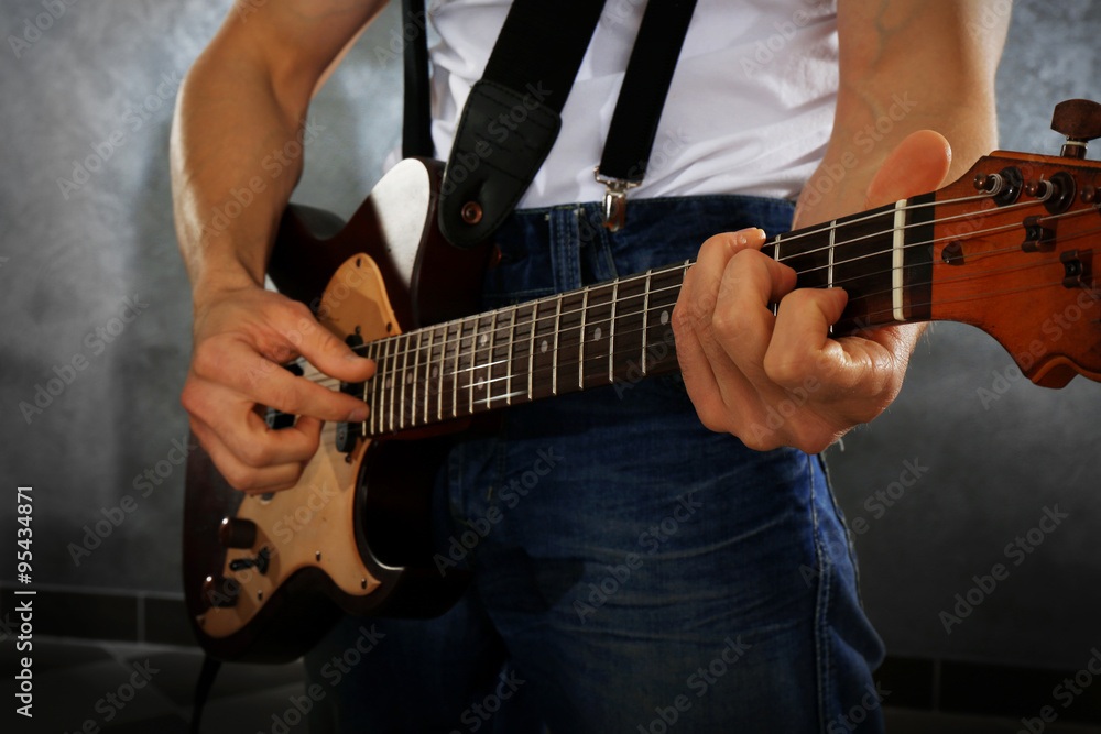 Fototapeta premium Young man paying guitar closeup