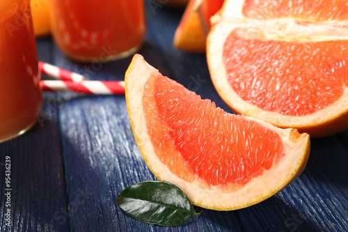 Grapefruit juice in bottles and fresh fruits on dark blue wooden background