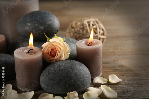 Beautiful relax composition of alight candles, pebbles and flowers on wooden background