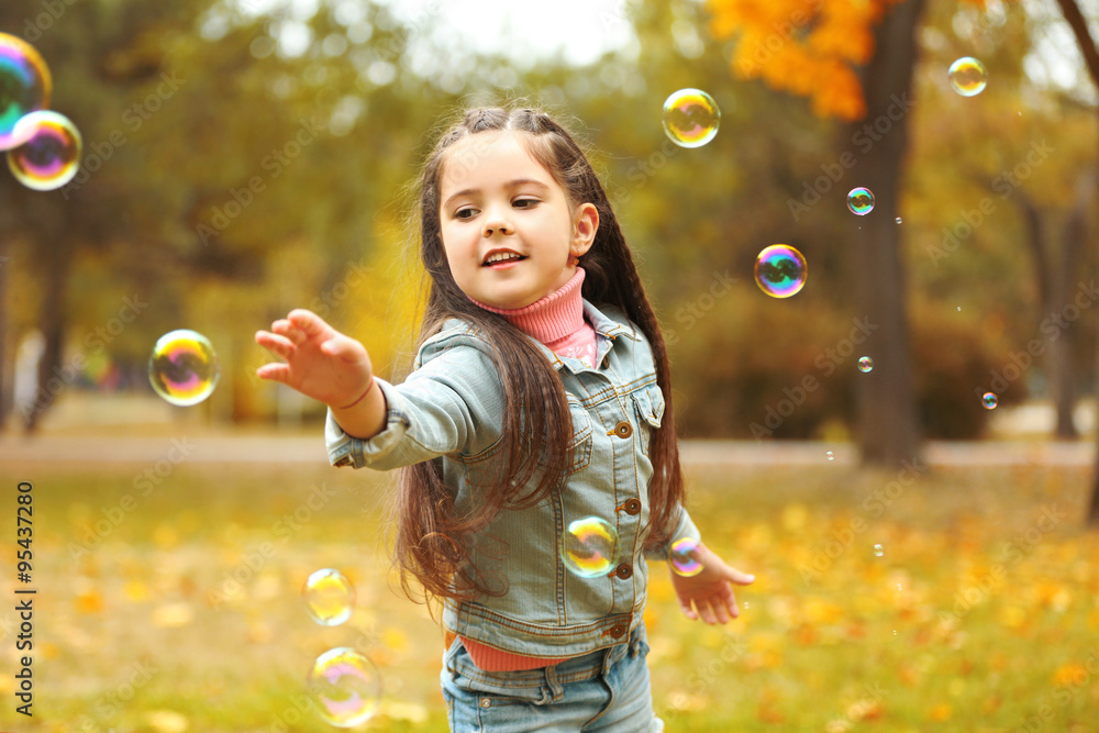 Cute girl playing with soap bubbles in park Cute girl playing with soap bubbles in park