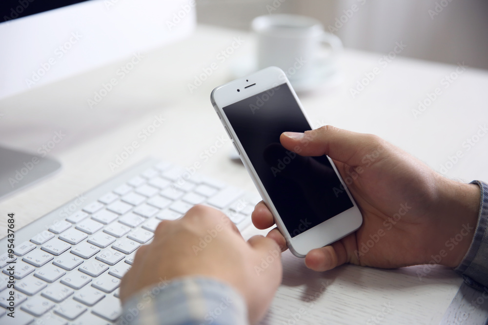 Young businessman using his phone and computer, close up