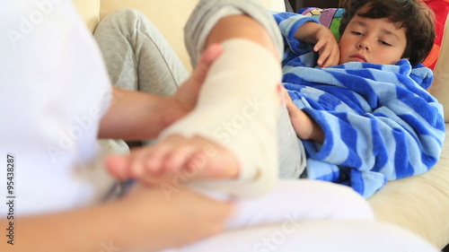 Doctor/nurse hands bandaging a child's sprained ankle.