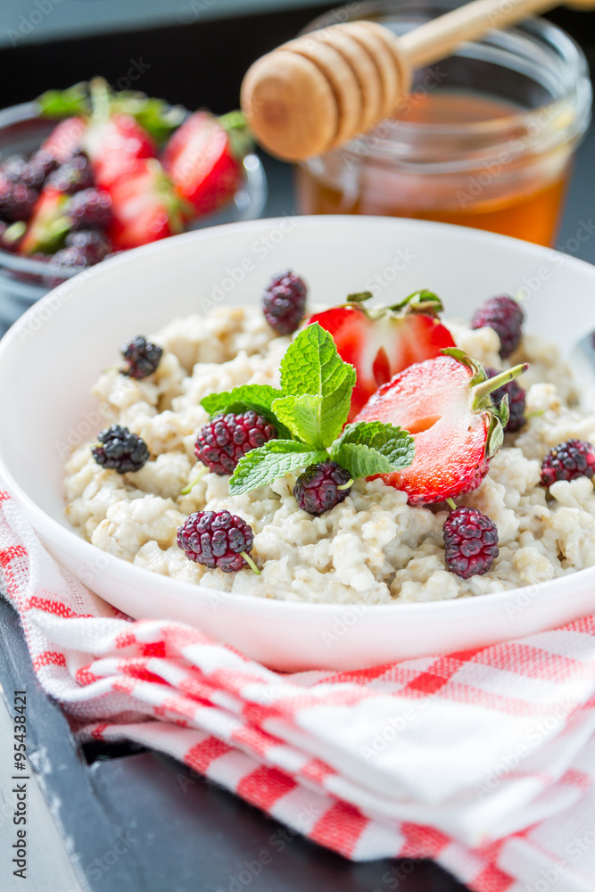 Breakfast - oatmeal with honey and berries, blue bowl Breakfast - oatmeal with honey and berries, blue bowl