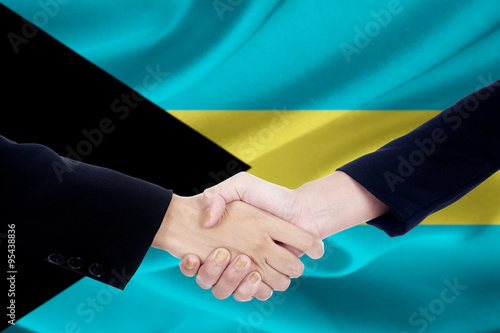 Two people shaking hands with flag of Bahamas