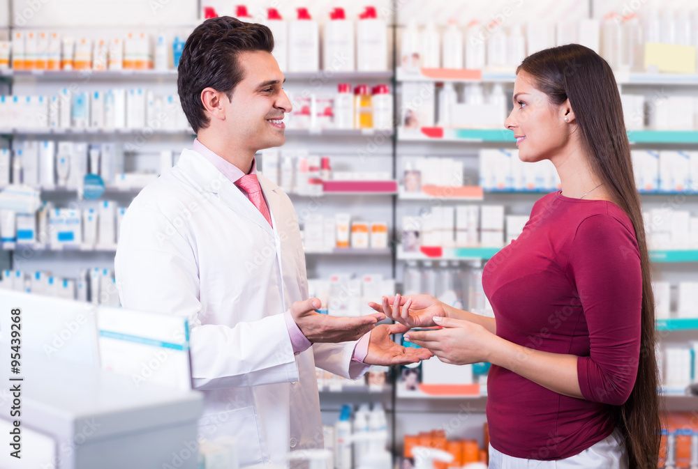 Professional pharmaceutist in drugstore helping girl