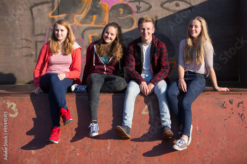 Portrait Of Teenage Friends Sitting In Skateboard Park