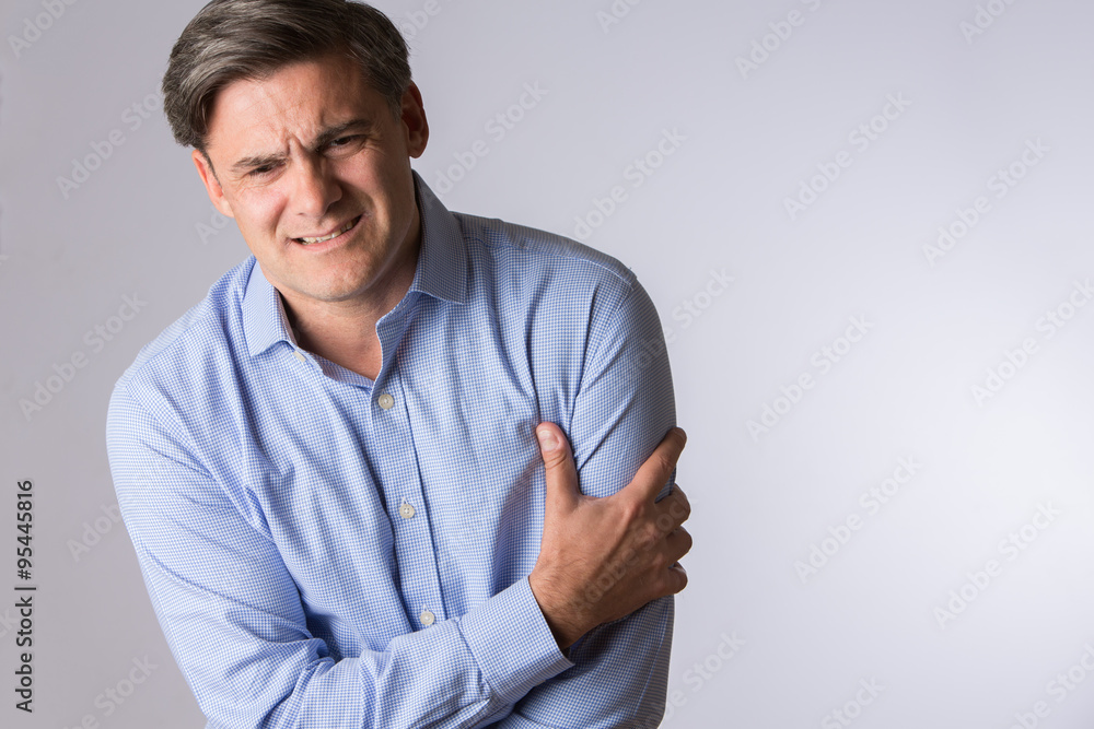 Studio Of Mature Man Clutching Arm As Warning Of Heart Attack