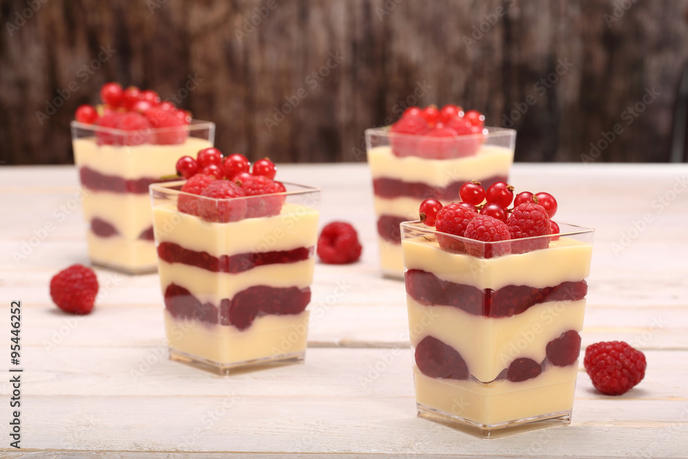 Pudding in a glass with fresh raspberries and currants on white Pudding in a glass with fresh raspberries and currants on white