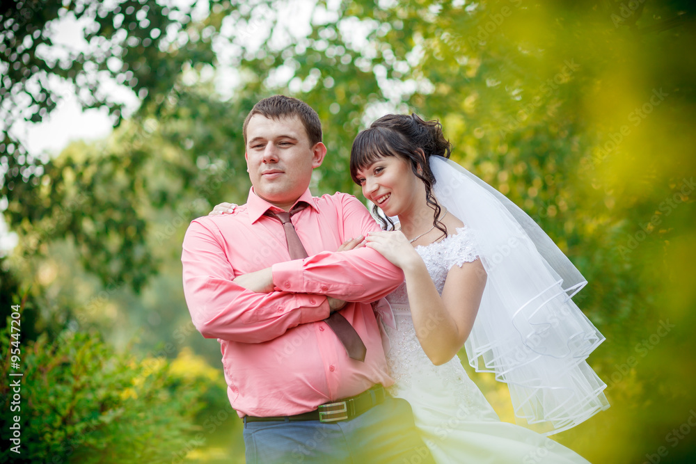 Naklejka premium bride behind the groom in park