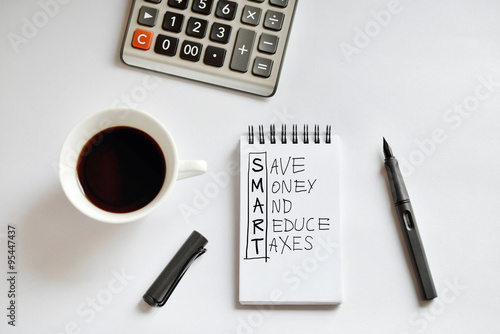 Coffee cup, spiral notebook, calculator, and pen on white backgr