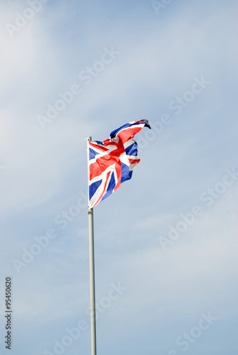 Flag of Great Britain. Color photo, blue sky with clouds background.