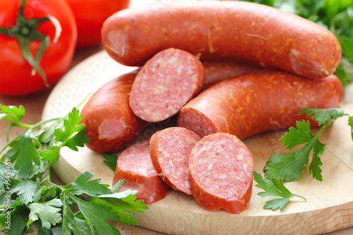 Smoked sausage with spices and vegetables on wooden table