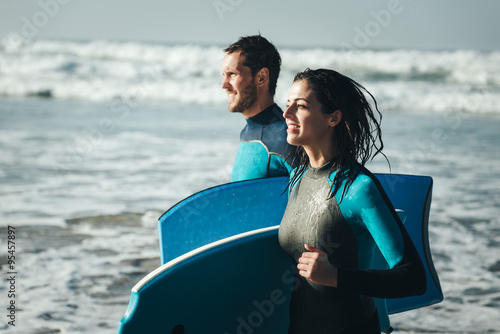 Tableau sur toile Young couple of bodyboard surfers runnign
