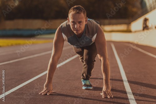 Athletic man standing in posture ready to run on a treadmill