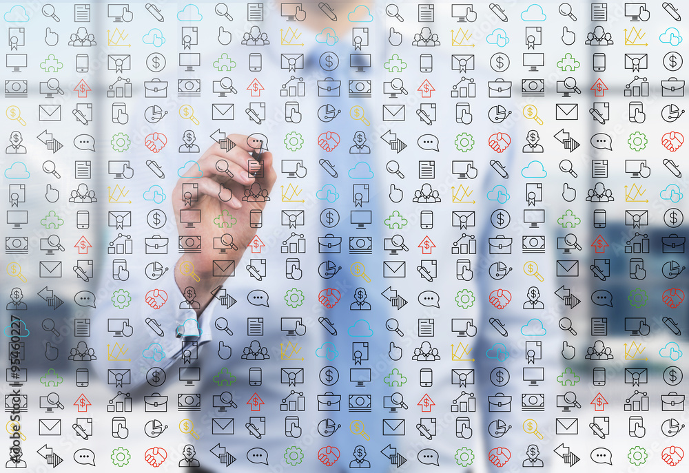 A business person is writing a numerous business and social media icons on the glass screen in the modern panoramic office. A business person is writing a numerous business and social media icons on the glass screen in the modern panoramic office.