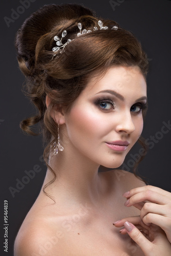 Beautiful brunette girl with perfect skin, evening make-up, wedding hairstyle and accessories. Beauty face