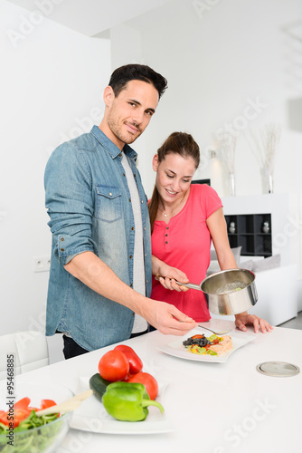 beautiful and happy young couple having fun cooking together fresh food in kitchen at home
