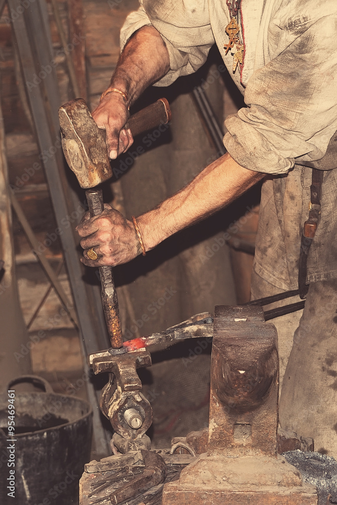 Blacksmith working metal with hammer