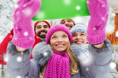 smiling friends with tablet pc in winter forest