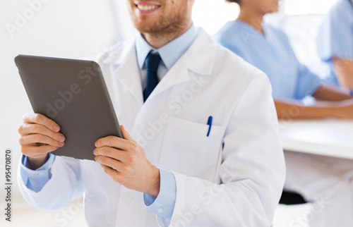 close up of happy doctor with tablet pc at clinic
